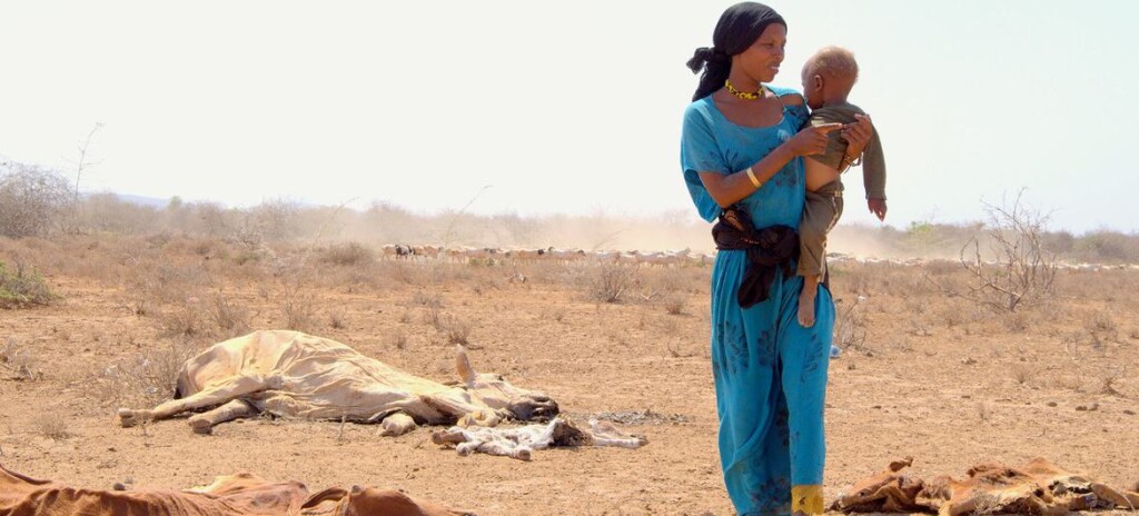 UNICEF/Oloo_. Una madre con su hijo en brazos caminado junto a los cadáveres del ganado muerto a causa de la grave sequía en Marsabit, en Kenya